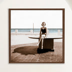Sepia photograph with colour touches of a 1950s woman seated by the sea at Playa Cojimar, framed in oak. Close view.