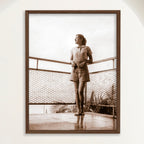 Sepia photograph of a 1950s woman on a balcony above Playa Cojimar in vertical format, framed in oak. Close view.