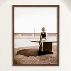 Sepia photograph of a 1950s woman seated by the sea at Playa Cojimar in vertical format, framed in oak. Close view.